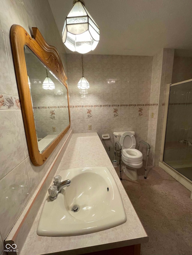 bathroom with tile walls, vanity, toilet, a shower with door, and a textured ceiling