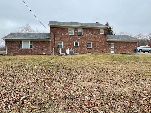 rear view of property featuring a lawn and central air condition unit