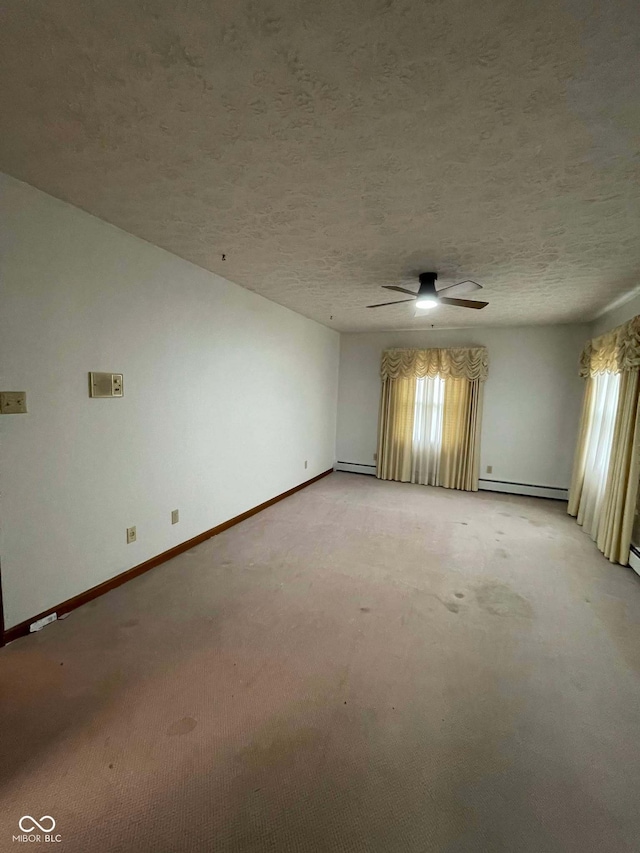 unfurnished room featuring a textured ceiling, a baseboard radiator, light colored carpet, and a healthy amount of sunlight