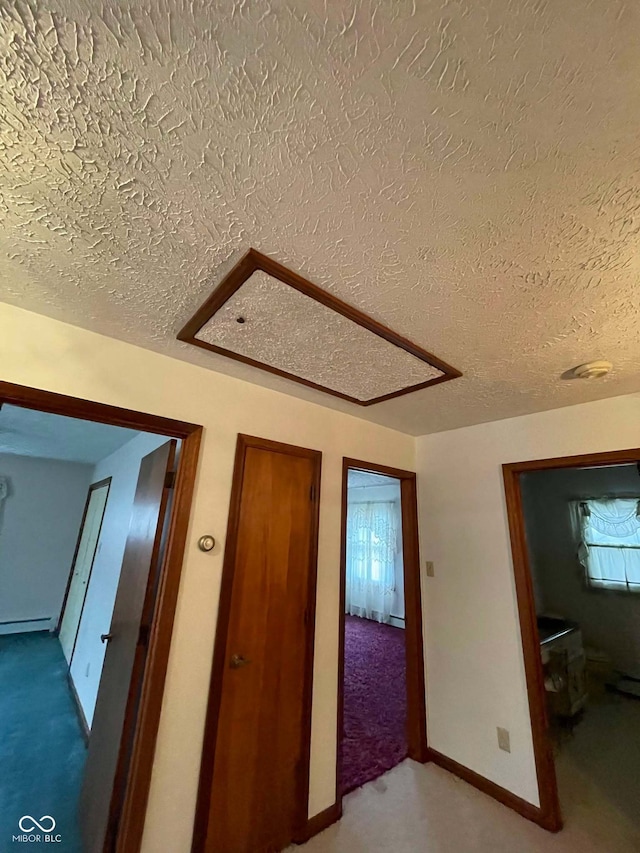 corridor with a baseboard radiator, carpet flooring, and a textured ceiling