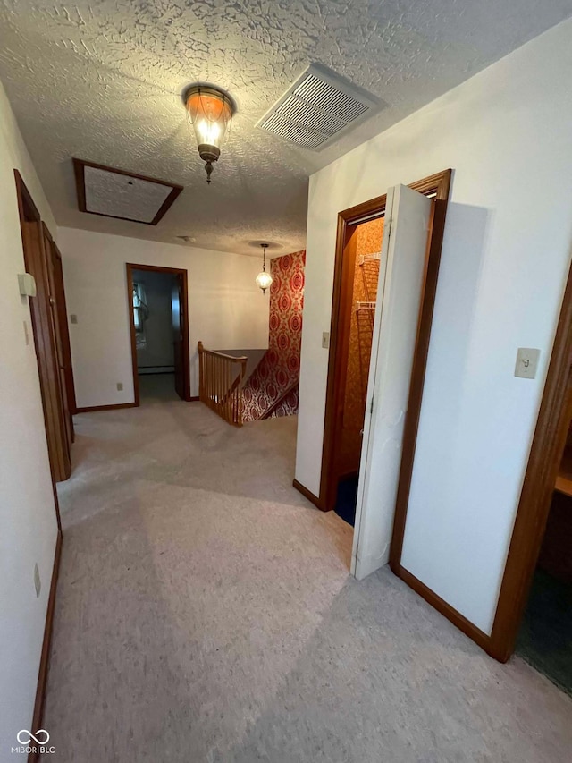 corridor with light carpet and a textured ceiling