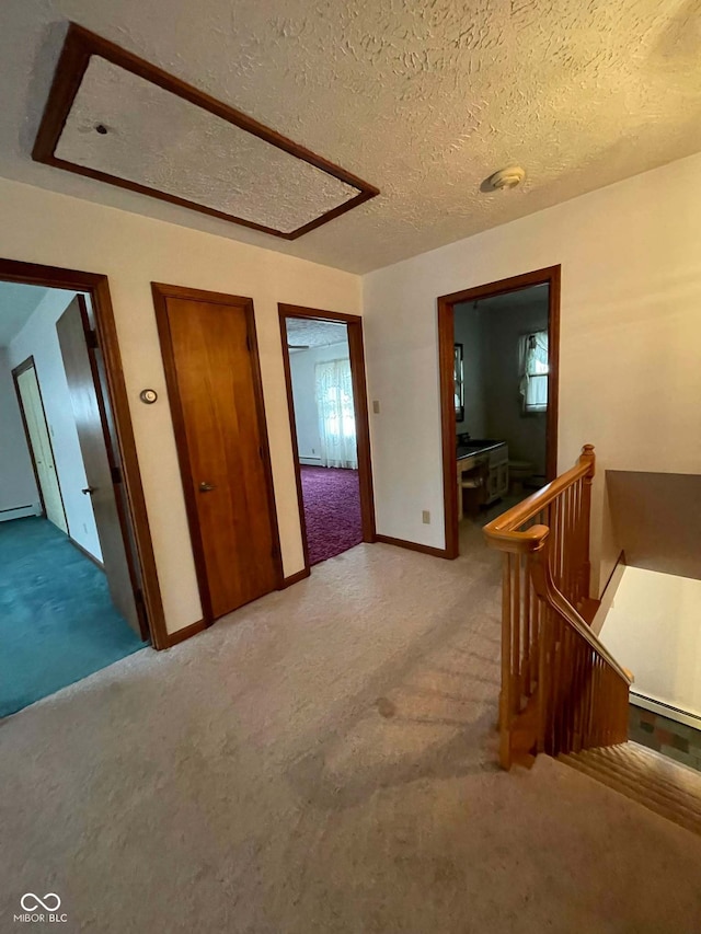 hallway featuring light colored carpet and a textured ceiling