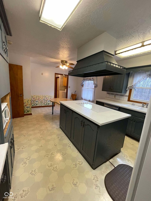 kitchen featuring ceiling fan, a kitchen island, sink, and a textured ceiling