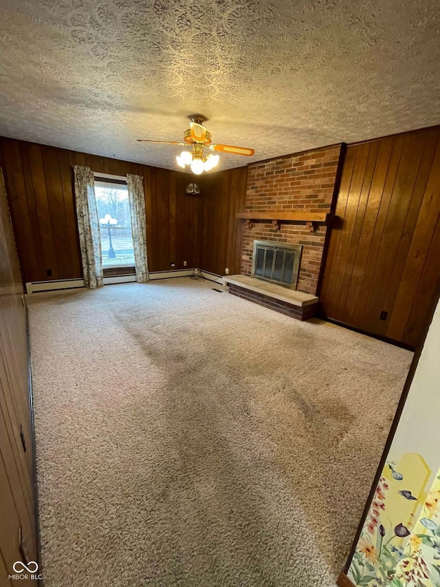 unfurnished living room featuring ceiling fan, wooden walls, carpet, a textured ceiling, and a brick fireplace