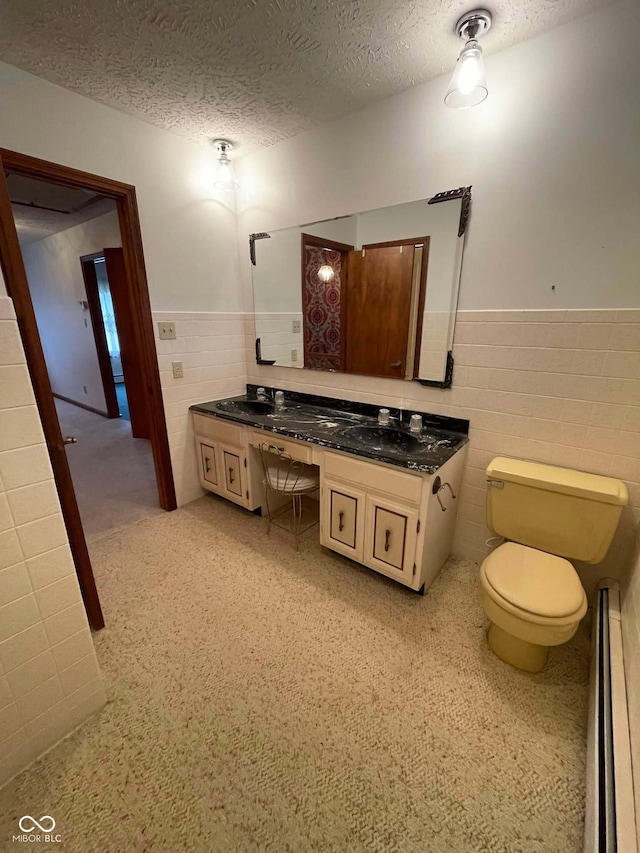 bathroom with tile walls, a baseboard heating unit, vanity, a textured ceiling, and toilet