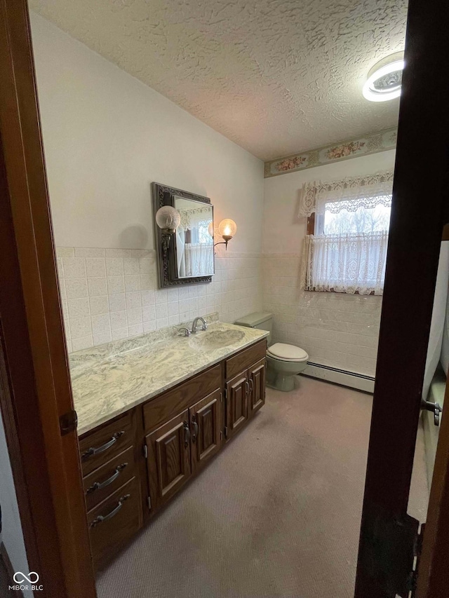 bathroom with tile walls, vanity, a textured ceiling, a baseboard radiator, and toilet