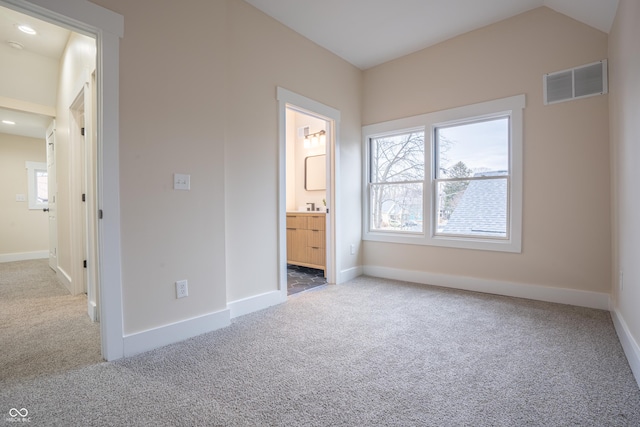 unfurnished bedroom featuring carpet, connected bathroom, and lofted ceiling