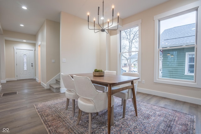 dining space with hardwood / wood-style floors and a notable chandelier