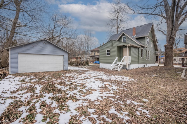 snow covered property featuring a garage and an outdoor structure