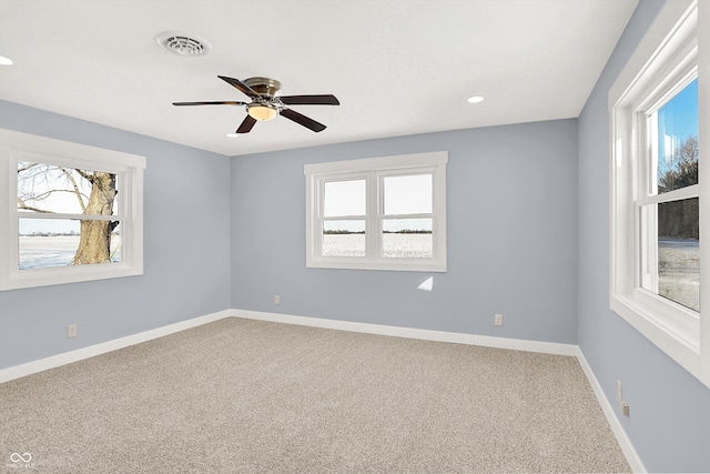 spare room with carpet, baseboards, visible vents, and a wealth of natural light