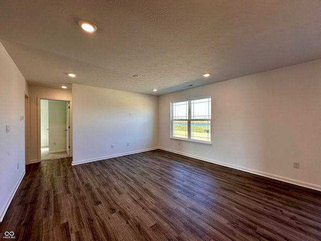 empty room with dark hardwood / wood-style flooring and a textured ceiling