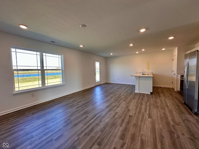 unfurnished living room with plenty of natural light, dark hardwood / wood-style floors, and a textured ceiling