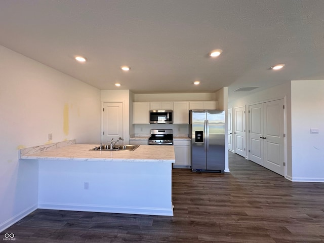 kitchen featuring appliances with stainless steel finishes, sink, white cabinets, dark hardwood / wood-style flooring, and kitchen peninsula