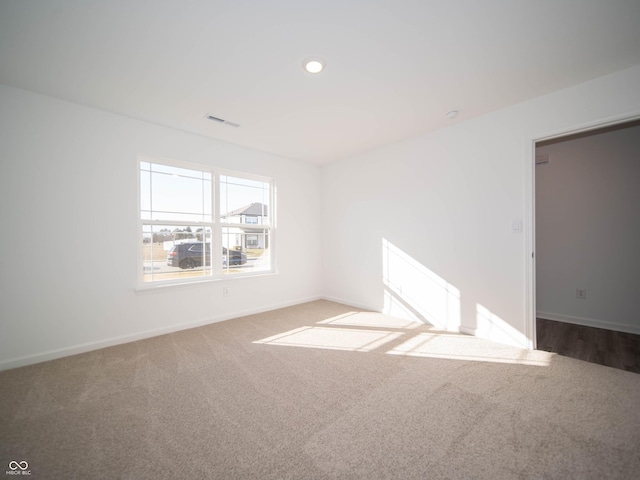 spare room featuring carpet floors, baseboards, visible vents, and recessed lighting