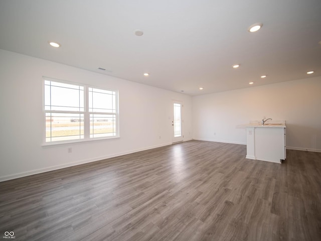 spare room featuring baseboards, dark wood-type flooring, recessed lighting, and a healthy amount of sunlight