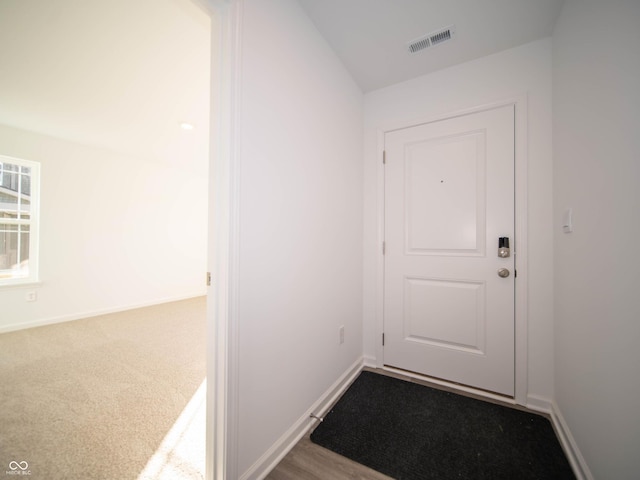 doorway to outside with carpet, visible vents, and baseboards