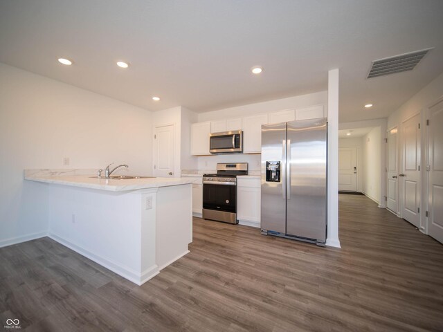 kitchen featuring visible vents, white cabinets, dark wood-style flooring, stainless steel appliances, and a sink