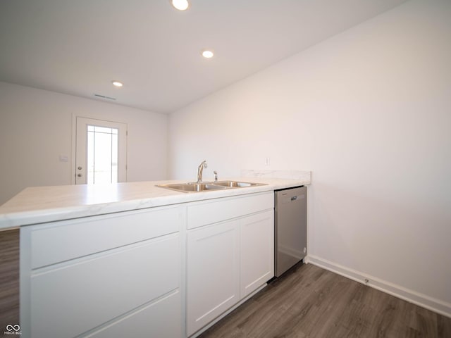 kitchen featuring a peninsula, a sink, white cabinetry, dishwasher, and dark wood finished floors