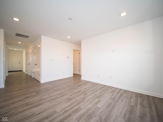 spare room featuring recessed lighting, wood finished floors, visible vents, and baseboards