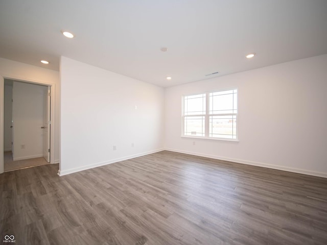 empty room with baseboards, wood finished floors, visible vents, and recessed lighting