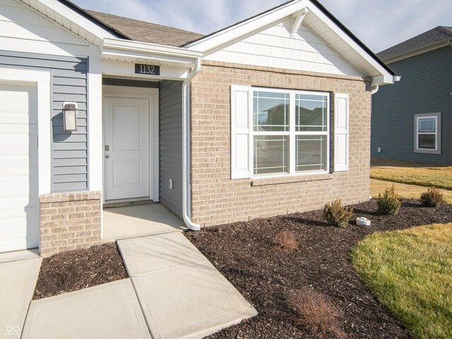 property entrance featuring brick siding and a shingled roof