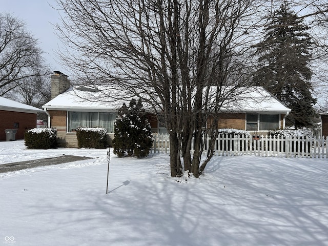 exterior space featuring a chimney, brick siding, and a fenced front yard