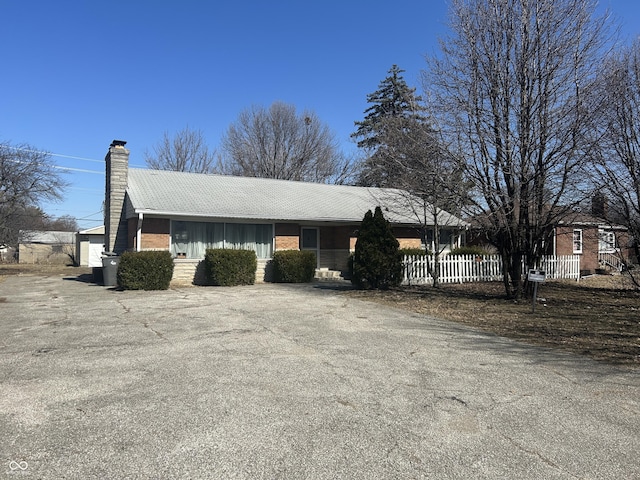 view of front of home featuring fence, brick siding, and a chimney