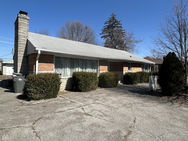 view of front of property with brick siding, a chimney, and a shingled roof