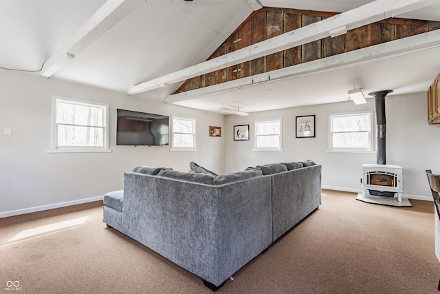 living room featuring a wood stove, baseboards, beam ceiling, and carpet flooring