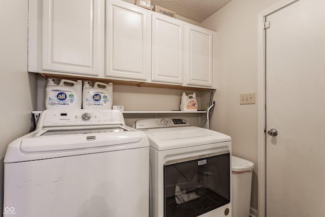 laundry room featuring washer and dryer, cabinet space, and a textured ceiling