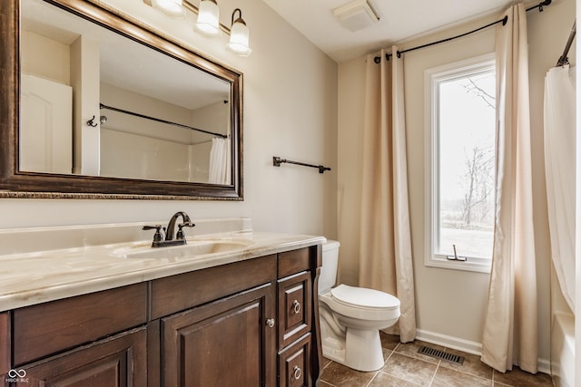 bathroom featuring vanity, toilet, visible vents, and a wealth of natural light