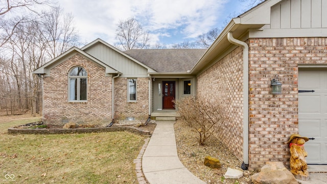 doorway to property with brick siding, a shingled roof, a yard, a garage, and crawl space