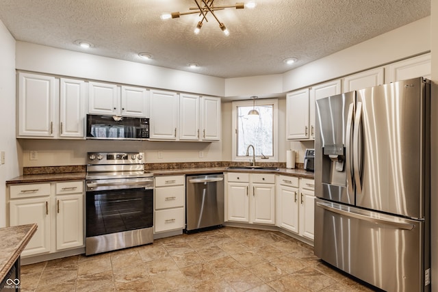 kitchen featuring a sink, stainless steel appliances, white cabinets, a textured ceiling, and dark countertops