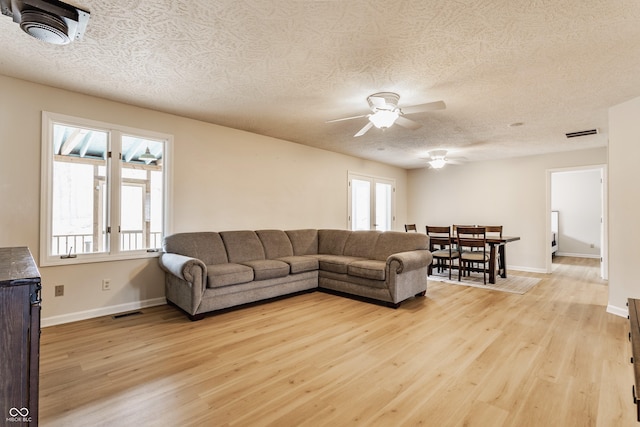 living room with visible vents, baseboards, and light wood-style floors