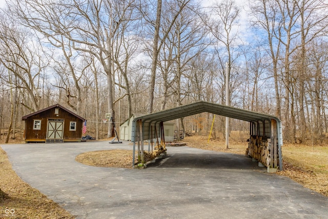 view of community with a carport, an outdoor structure, and driveway