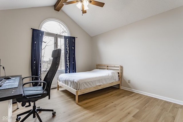 bedroom featuring light wood finished floors, vaulted ceiling with beams, baseboards, and a ceiling fan