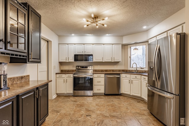 kitchen featuring a sink, stainless steel appliances, glass insert cabinets, white cabinetry, and dark countertops