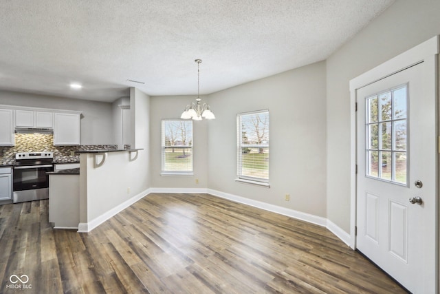 kitchen featuring a breakfast bar, white cabinetry, stainless steel electric range oven, hanging light fixtures, and dark hardwood / wood-style flooring