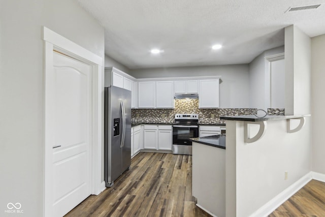 kitchen featuring dark wood-type flooring, tasteful backsplash, appliances with stainless steel finishes, kitchen peninsula, and white cabinets