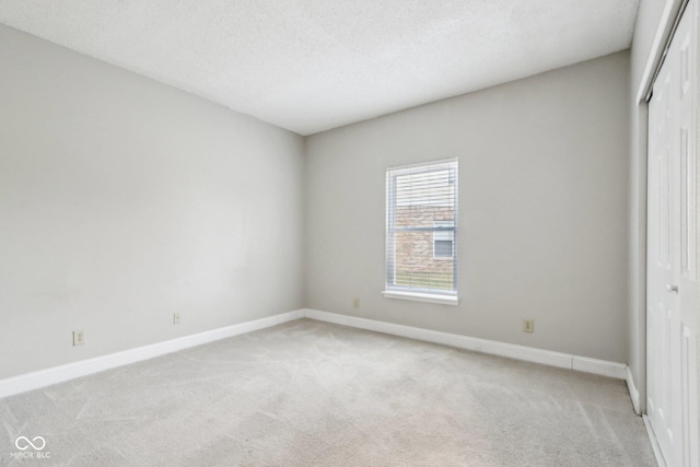 unfurnished bedroom with light colored carpet, a textured ceiling, and a closet