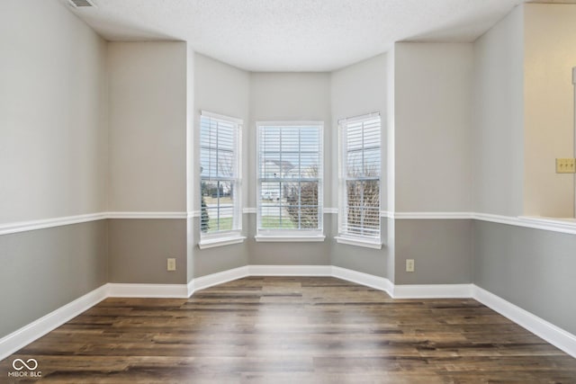 spare room featuring dark hardwood / wood-style floors and a textured ceiling