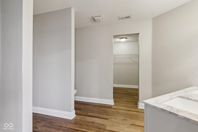 bathroom featuring vanity, hardwood / wood-style floors, toilet, and a textured ceiling