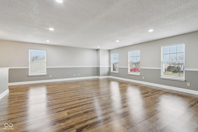 empty room with dark hardwood / wood-style floors and a textured ceiling