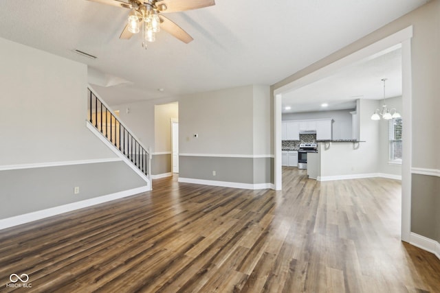 unfurnished living room with dark hardwood / wood-style flooring and ceiling fan with notable chandelier