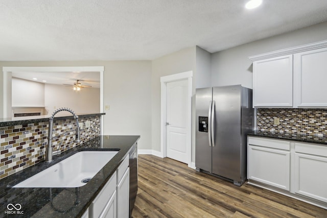 kitchen with sink, appliances with stainless steel finishes, white cabinets, dark hardwood / wood-style flooring, and dark stone counters