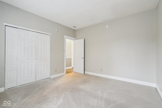 unfurnished bedroom featuring light colored carpet and a closet