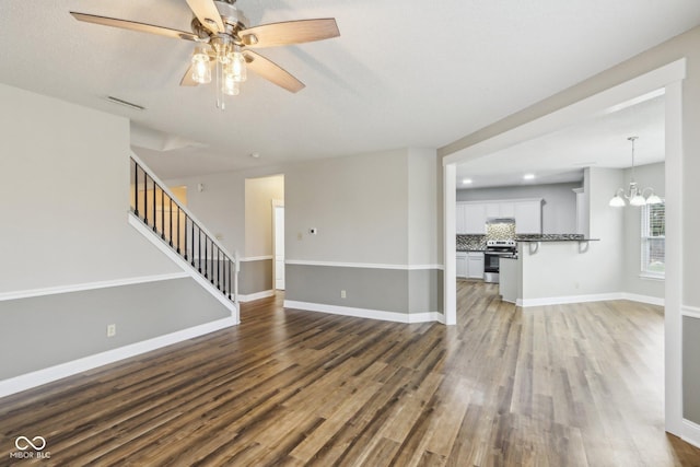 unfurnished living room featuring dark hardwood / wood-style flooring and ceiling fan with notable chandelier