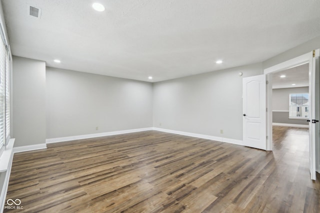 spare room featuring dark hardwood / wood-style floors and a textured ceiling