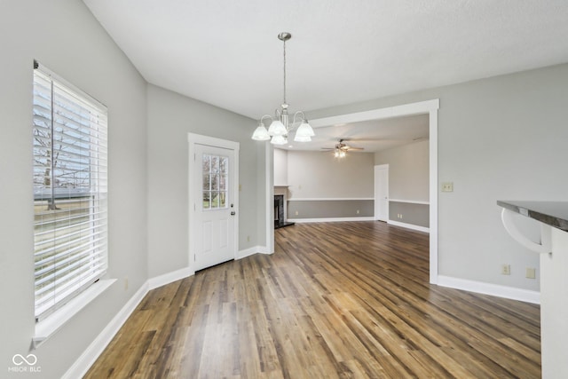 unfurnished living room with ceiling fan with notable chandelier, hardwood / wood-style floors, and a wealth of natural light