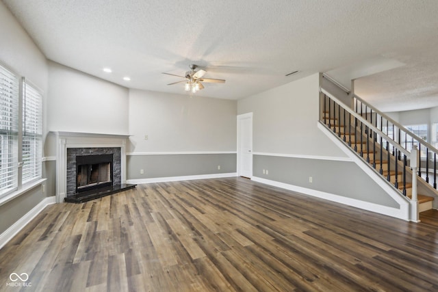 unfurnished living room with hardwood / wood-style flooring, ceiling fan, a fireplace, and a textured ceiling